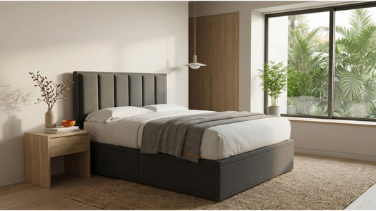 Grey upholstered bed frame in a calm Singapore bedroom with bamboo plants, wood bedside table, and natural daylight