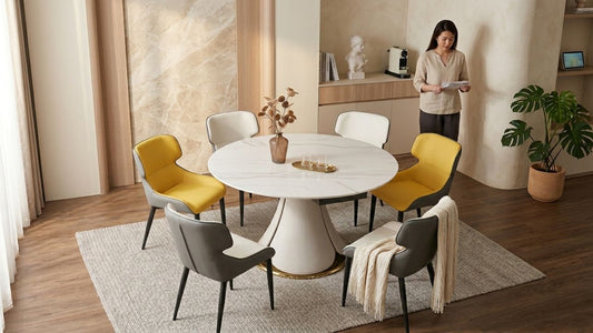 Modern round marble dining table in a Singapore apartment with mixed grey and yellow dining chairs, warm wood accents, and minimalist contemporary interior styling.