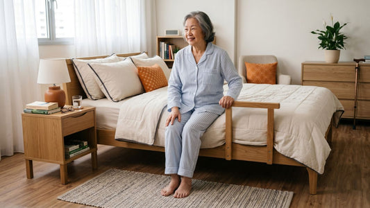 Elderly woman sitting on a supportive mattress with bed rail in a warm Singapore bedroom, showing comfort and mobility for older sleepers