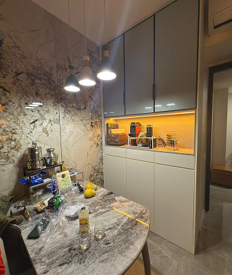 Modern kitchen with table, bottle, and lighting fixture.